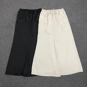 Detailed flat lay of black and beige satin maxi skirts with elastic drawstring waist