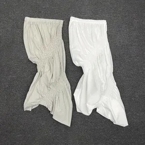 Detailed view of white and striped smocked skirts with elastic texture and irregular hem