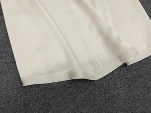 Detailed view of the smooth cream satin fabric and premium stitching on the skirt hem