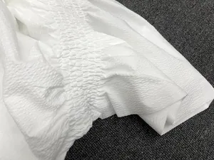 Detail of white high-waist skirt featuring elastic smocking and textured seersucker fabric