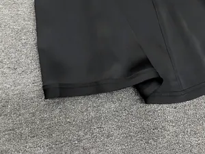 Close-up of black satin skirt featuring precise flatlock stitching and premium matte fabric