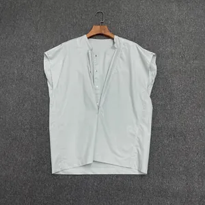 Detail of light grey-green sleeveless shirt featuring a crossover V-neck and metal buttons