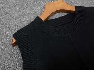 Detailed view of black knitted wool vest showing ribbed round neck and sleeve edges