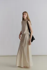 Elegant beige satin long A-line skirt paired with matching sleeveless top and black bag