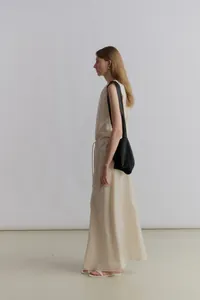 Side view of a minimalist cream satin A-line maxi skirt with adjustable drawstring waist