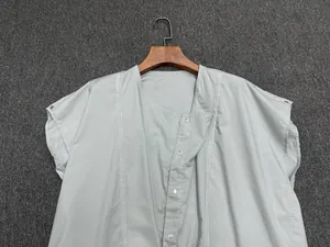 Detail of light grey short-sleeve shirt with side button closure and metal snaps