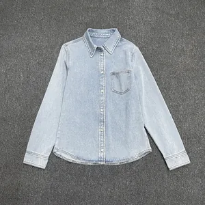 Close-up of light blue denim shirt showing front pocket and classic collar detail
