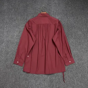 Detail of the pleated back design and matte wine red fabric on a cotton long sleeve shirt
