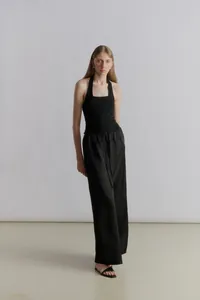 Detail of minimalist black two-piece set featuring halter neck top and wide-leg trousers