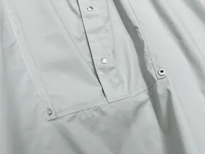 Close-up of light gray short-sleeve shirt with metal buttons and herringbone trim details