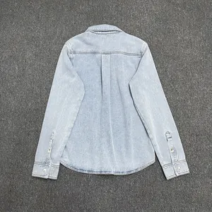 Back view of light blue denim shirt showing the shoulder yoke, center pleat, and curved hem