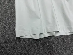 Detail view of light grey cotton hem showing high-quality double-needle stitching and fabric