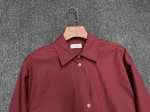 Detail of dark burgundy cotton shirt with white buttons and classic lapel collar