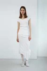 Detail of white asymmetric midi skirt featuring pleated ruffles and ribbed knit texture