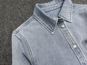 Close-up of light blue denim shirt collar with pearl buttons and white stitching
