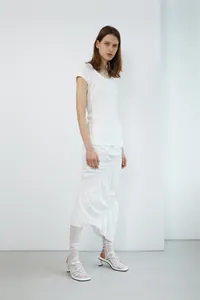 Detail of white high-waisted fishtail skirt featuring asymmetric ruffles and ruched design