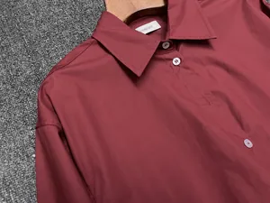 Detailed shot of dark red cotton shirt with classic collar and white buttons