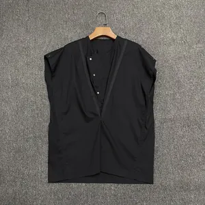 Detail of black sleeveless shirt with asymmetric V-neck and silver metal snap buttons