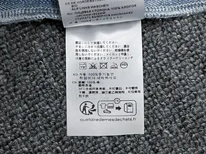 Detail shot of care label on 100% organic cotton blue denim shirt with washing instructions