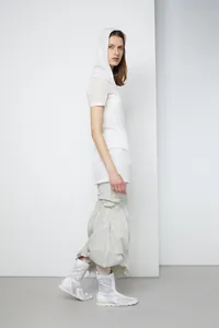 Detail of high waist irregular fishtail skirt with pleated texture and white boots
