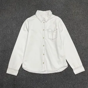 Detail of white shirt showing contrast stitching, dark buttons, and a front pocket
