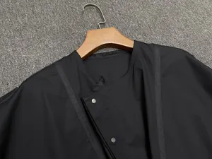 Close-up of black short-sleeve shirt with diagonal overlap and silver metal snap buttons