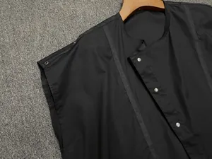 Detail of round neck black sleeveless top with silver buttons and textured binding