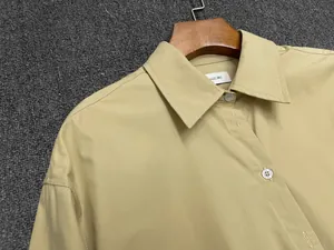 Close-up of khaki cotton shirt collar with neat stitching and white buttons