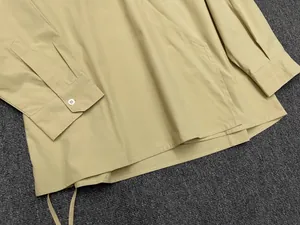 Detail view of khaki cotton shirt sleeve with button cuffs and fine stitching textures