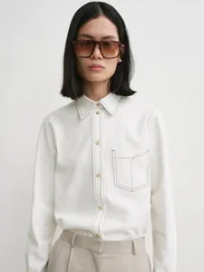 Close-up of white cotton shirt with brown contrast stitching and chest pocket detail