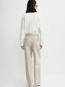 Rear view of white button-down shirt and beige high-waist trousers on a model