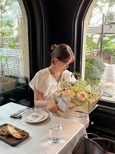 Blouse blanche à volants élégante avec collier de perles et bouquet de roses champagne