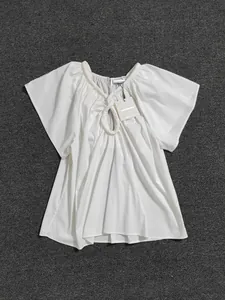 Détail de l'encolure à anneau circulaire et design ajouré sur une blouse d'été blanche
