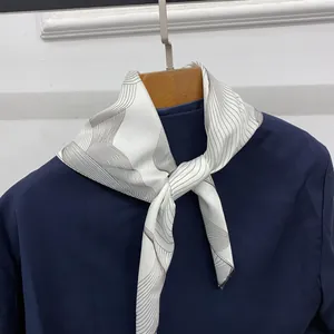 Detail of silk scarf with grey flowing patterns knotted on a navy blue shirt collar