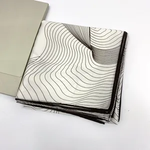 Detailed view of silk scarf featuring wave patterns and fine rolled edges with gift folder