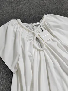Détail de la blouse blanche à manches courtes avec encolure plissée et goutte d'eau