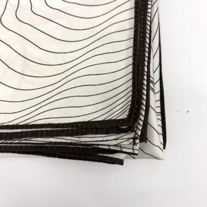 Close-up of geometric wave patterns on off-white silk scarf with dark stitched edges