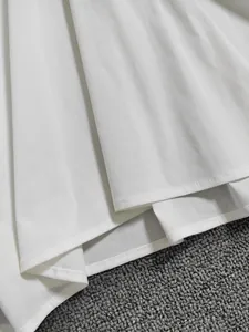 Gros plan du chemisier blanc à manches courtes avec texture verticale et coutures doubles