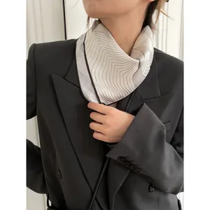 Elegant geometric print silk scarf with wavy lines, styled with a professional grey blazer