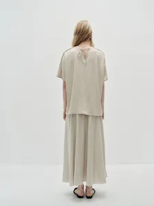 Back view of oatmeal elastic waist pleated maxi skirt and tie-back short sleeve top set