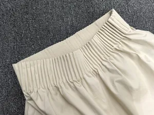 Detail of high elastic waistband with gathered pleats on beige cotton A-line skirt