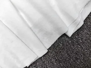 Macro view of white pleated cotton fabric detail showing fine texture and hem stitching
