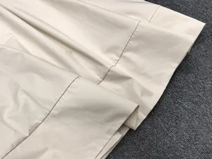 Close-up of clean stitching and hem detail on the light beige cotton A-line skirt