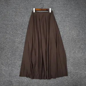 Close-up of a dark brown long A-line skirt with smooth waist hanging on a wooden hanger