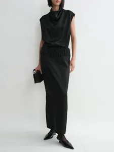 Detail of elegant black satin maxi skirt featuring delicate feather tassels at the waist