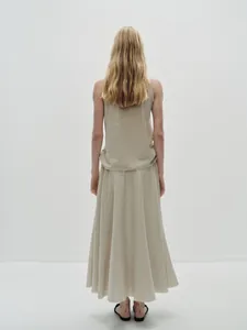 Detail of minimalist beige knitted two-piece set featuring a maxi A-line skirt and vest