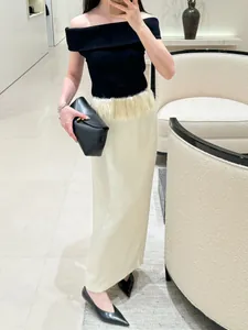 Detail of elegant satin maxi skirt with soft feather waist trim and straight silhouette