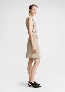 Detail of a beige striped ribbed knit vest paired with a matching belted A-line skirt