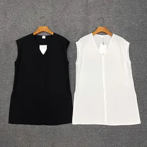 Detail showing simple black and white V-neck sleeveless tops hanging on wooden hangers