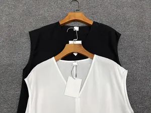 Close-up of minimalist black and white V-neck sleeveless tops on wooden hangers